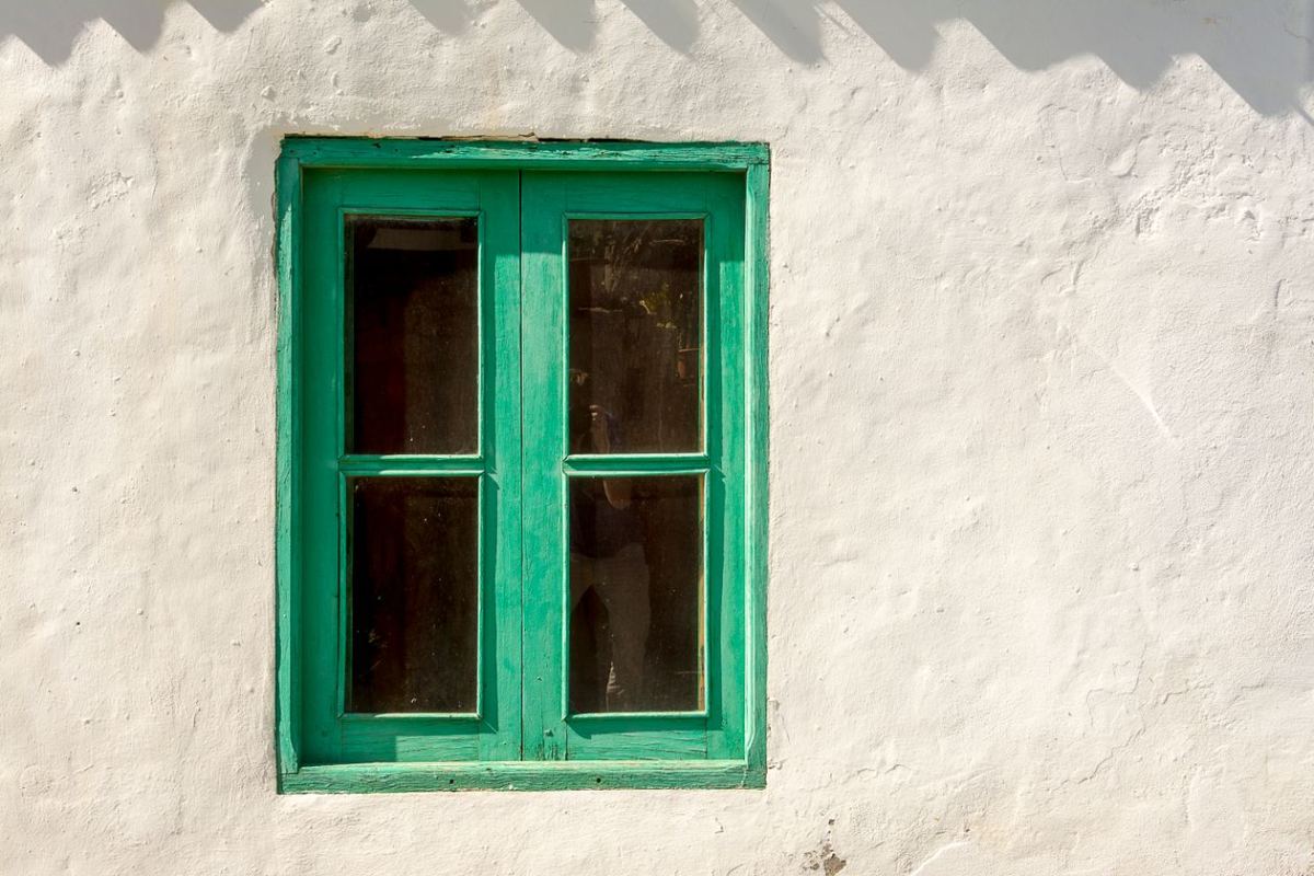 Fenêtre à cadre en bois vert sur le mur blanc d'une ancienne maison