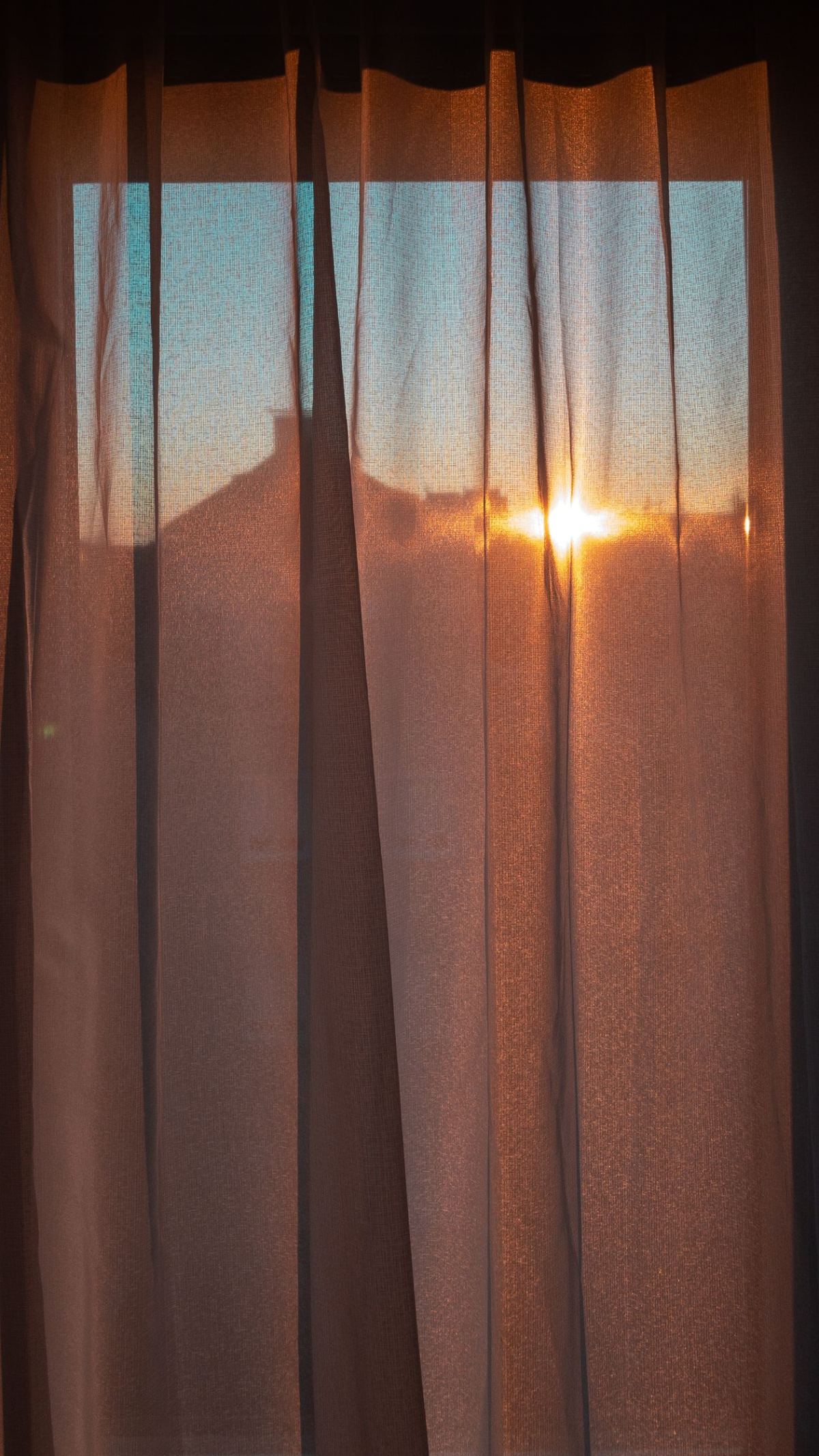 Voilage laissant passer la lumière du soleil levant à travers une fenêtre